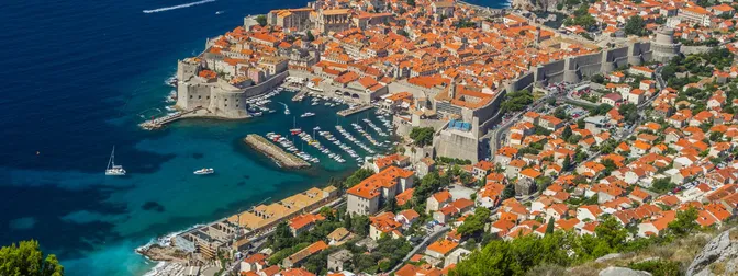 View over Dubrovnik's Old Town rooftops, harbor, and fortress walls from above