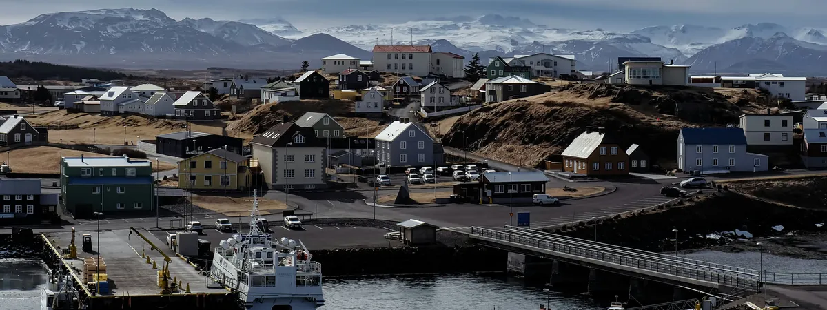 Stykkishólmur harbor with the Breiðafjörður ferry at the pier, colorful timber houses on the ridge above and snow-capped Snæfellsnes mountains beyond
