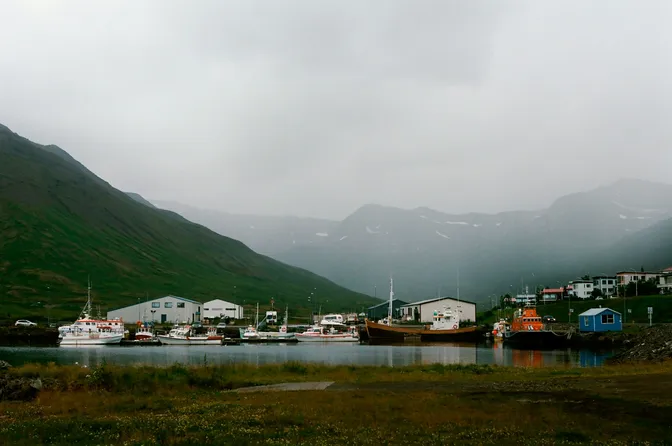 Fishing boats moored in a quiet harbor near Stykkishólmur, mountains rising behind