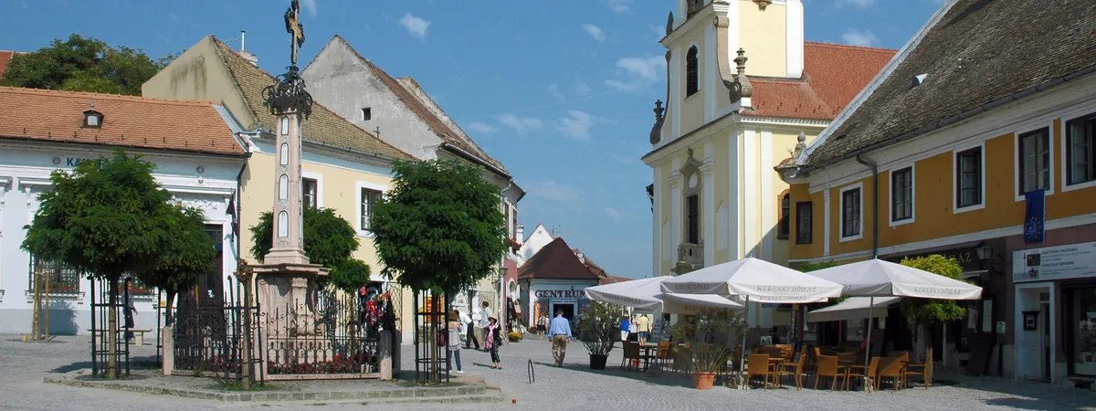 Szentendre's triangular Fő tér main square, with the 1763 Plague Cross, café terraces, and a Baroque church tower