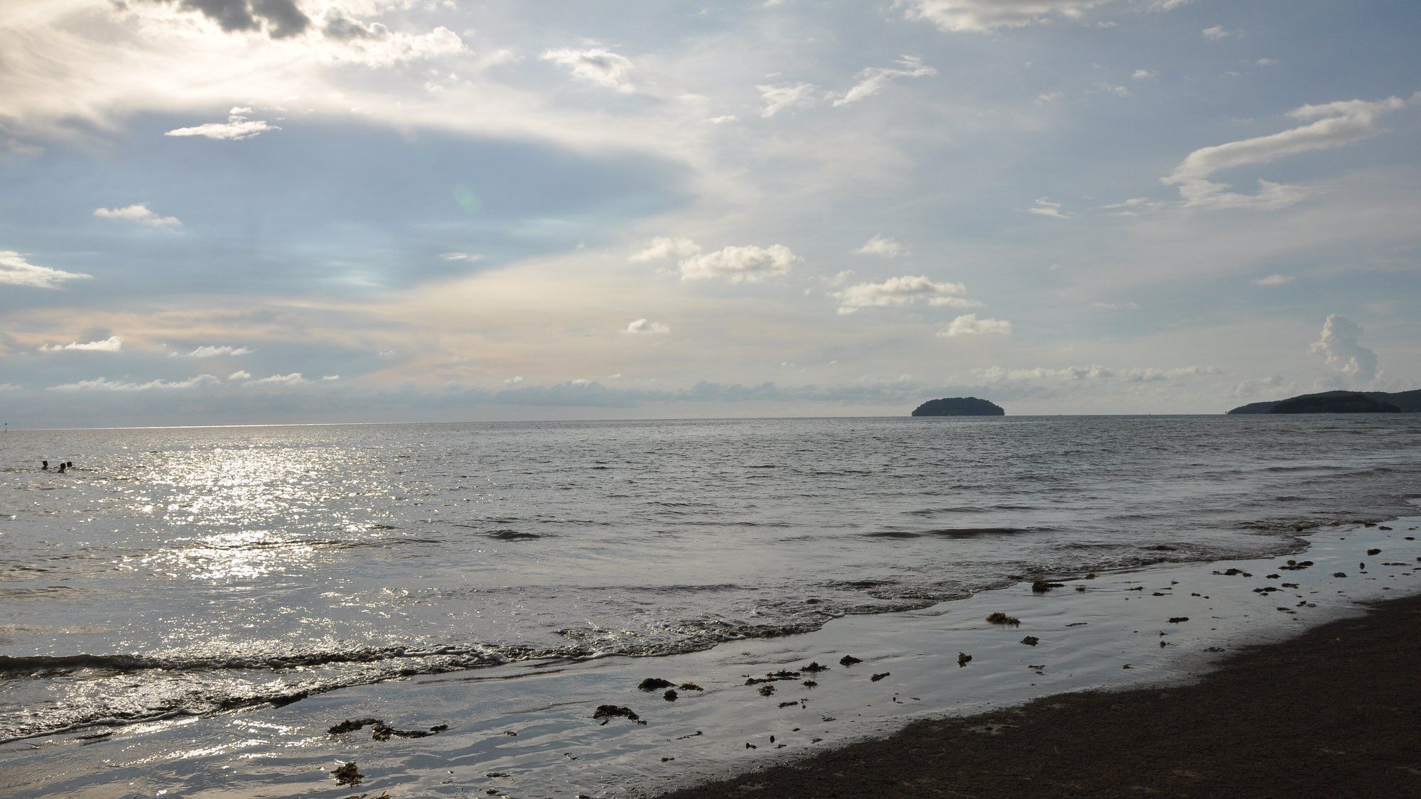 The sand and calm water of Tanjung Aru Beach, with the islands of Tunku Abdul Rahman Marine Park visible offshore