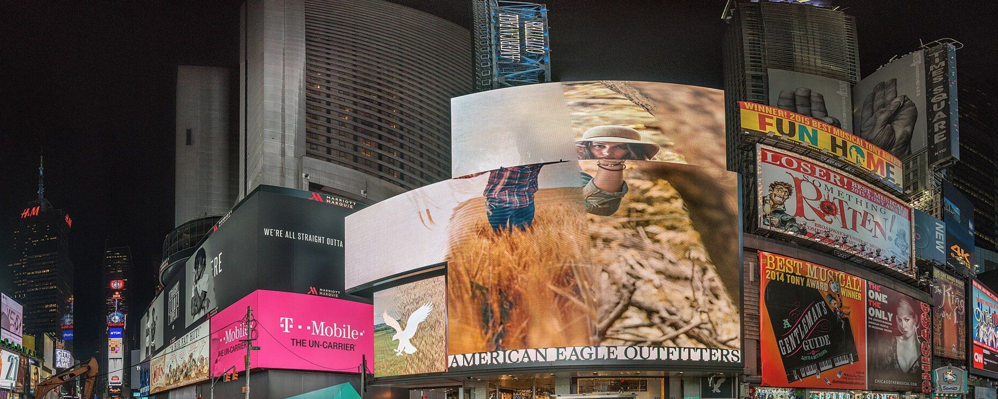 Times Square lit up at night with giant billboards and Broadway show marquees above the storefronts