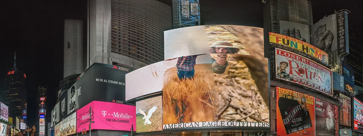 Times Square lit up at night with giant billboards and Broadway show marquees above the storefronts