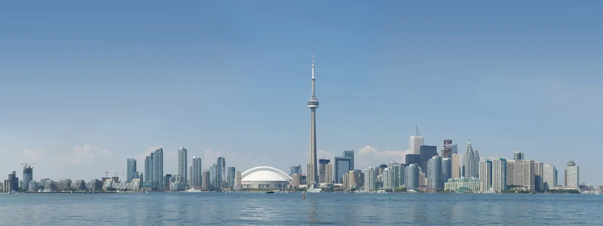 Toronto skyline seen across the water from Centre Island, with the CN Tower rising above the downtown towers and Rogers Centre's dome