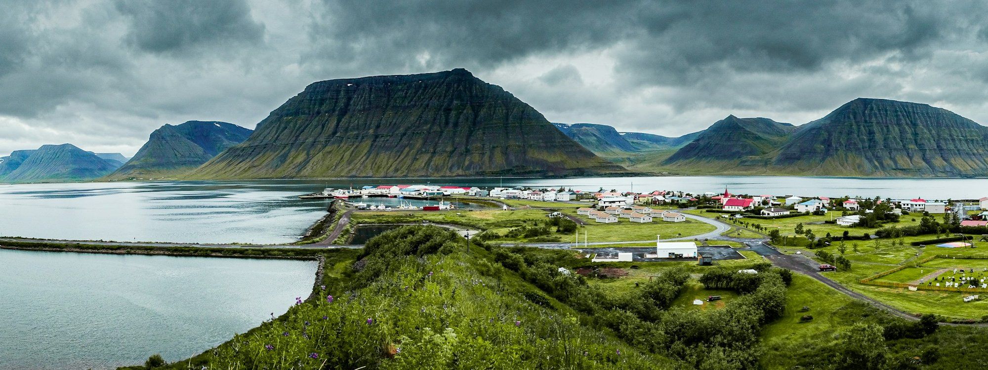 Ísafjörður spread along its sandspit in Skutulsfjörður under a flat-topped fjord mountain, with the harbour on one side and the fjord on the other