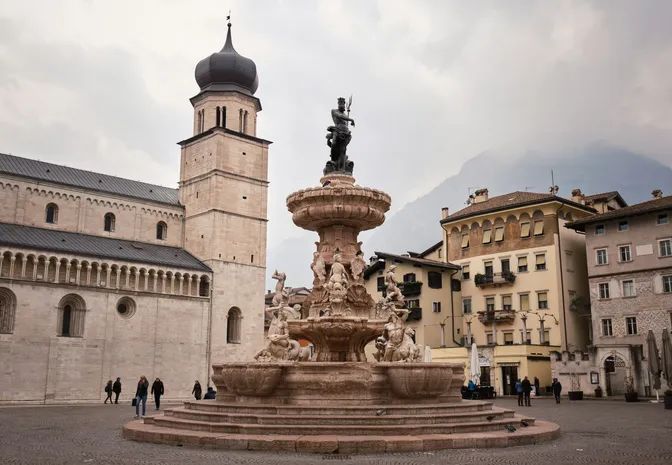 The Neptune fountain on Trento's Piazza Duomo, with the cathedral bell tower and painted facades around it
