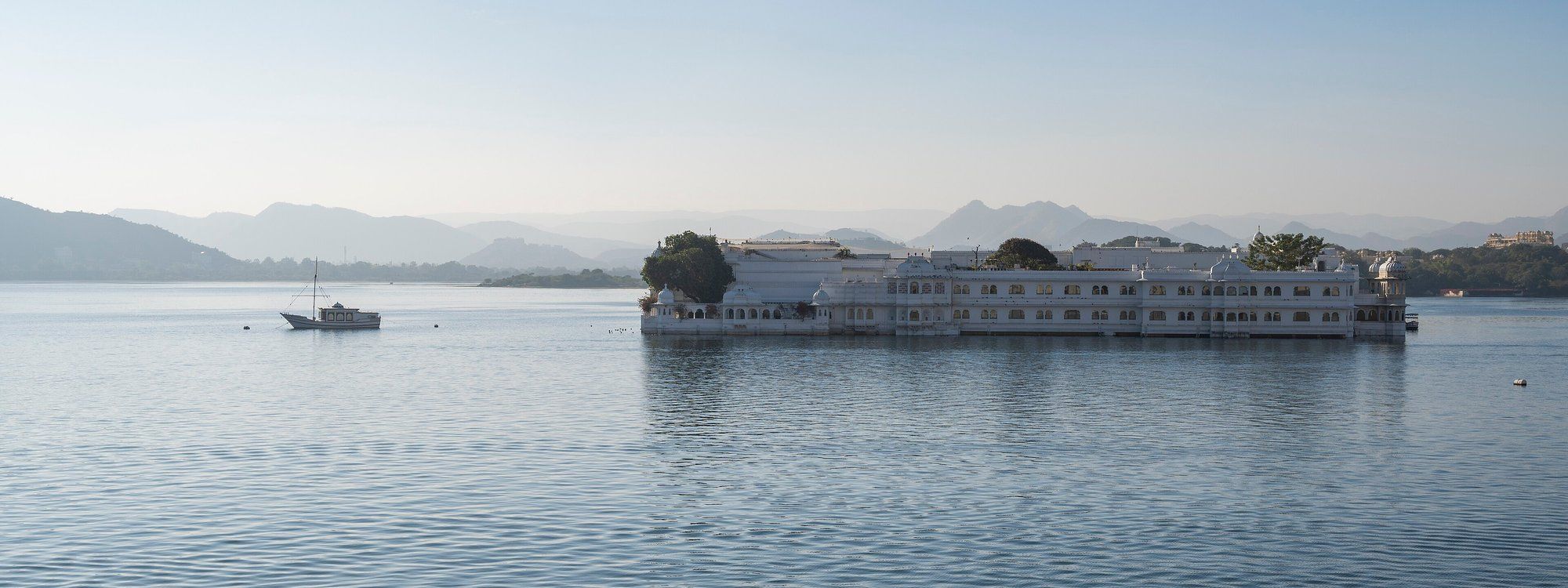 The Taj Lake Palace floating on Lake Pichola at sunrise, seen from the City Palace