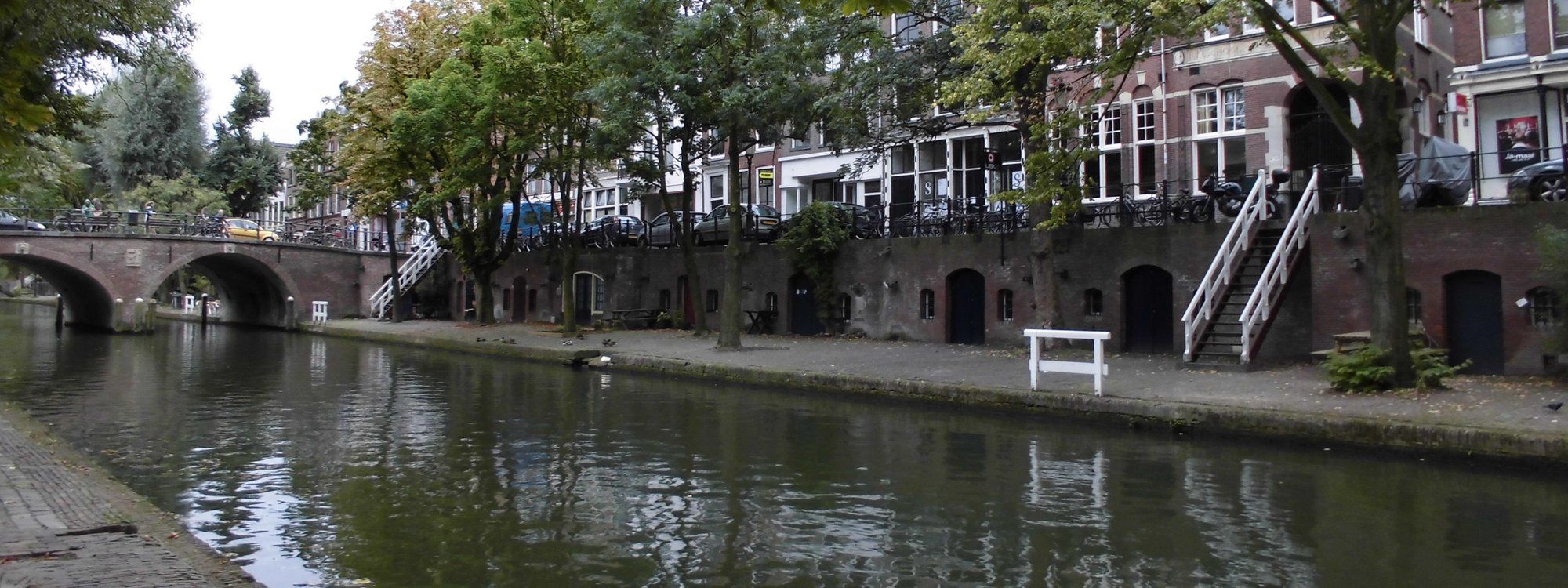 The Oudegracht canal in Utrecht at wharf level, lined with cellar doors, cafes, and a stone bridge
