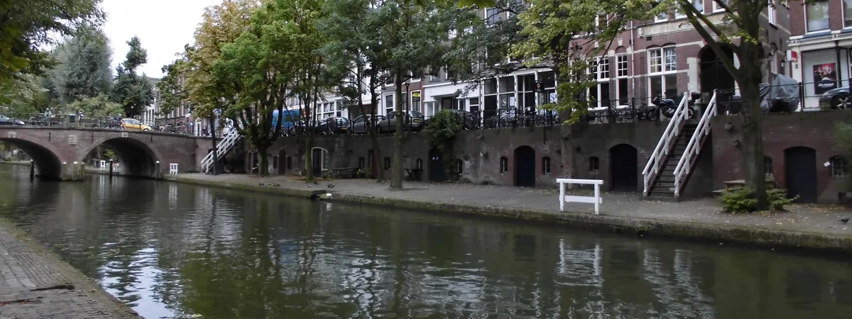 The Oudegracht canal in Utrecht at wharf level, lined with cellar doors, cafes, and a stone bridge