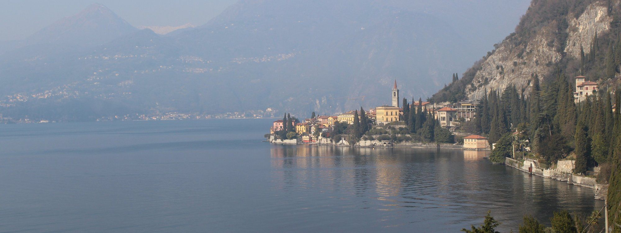 Varenna’s coloured houses and bell tower on their headland above Lake Como, with the mountains of the western shore behind