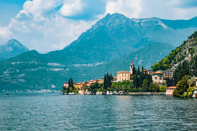 Varenna seen from the water, its lakeside villas and church tower below the mountains of Lake Como