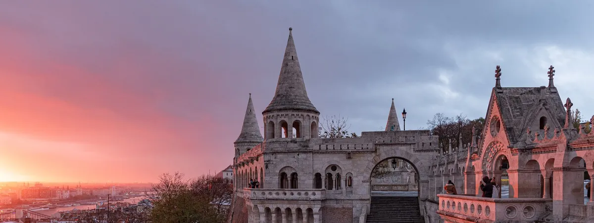 Las torretas cónicas y arcadas del Bastión de los Pescadores con vistas a Budapest al atardecer