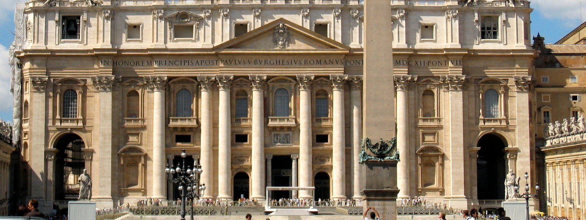 The facade of St. Peter's Basilica and the obelisk in St. Peter's Square, seen from the piazza with crowds gathered below