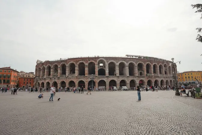 The Roman amphitheatre of the Arena di Verona seen across the marble paving of Piazza Bra