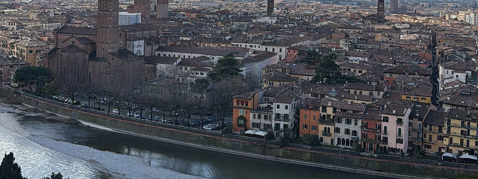 Verona’s old-town roofs and campaniles inside the bend of the Adige, seen from Castel San Pietro