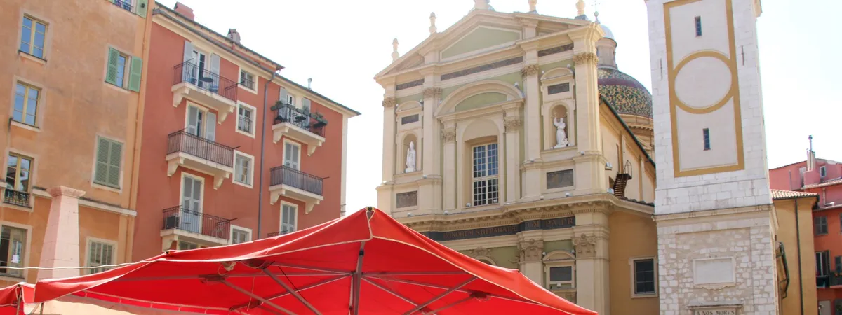 Red café umbrellas on Place Rossetti facing the Baroque facade of Cathédrale Sainte-Réparate in Vieux Nice