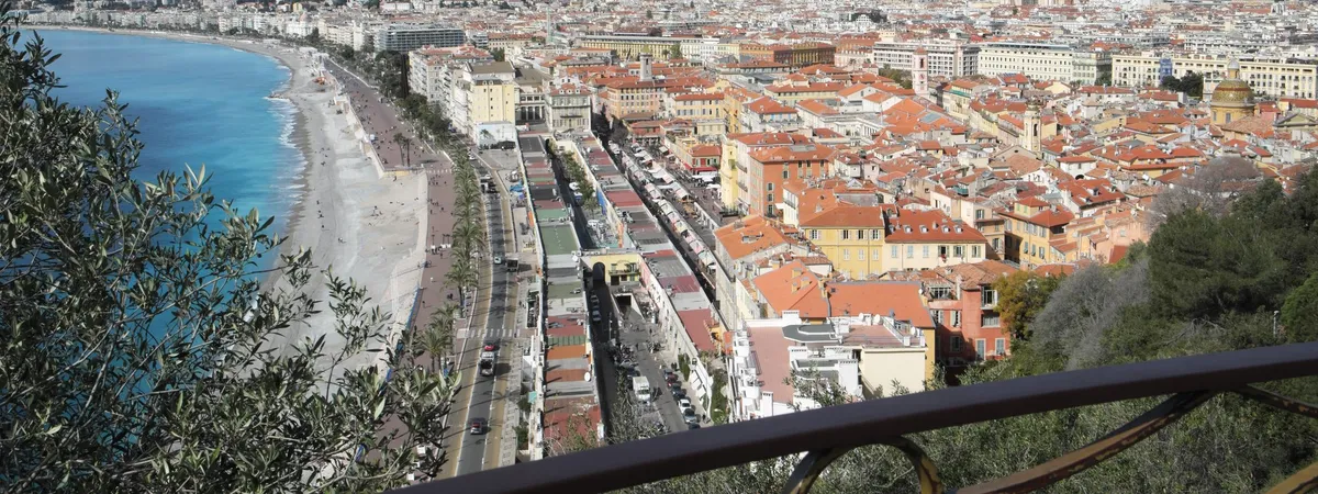 Aerial view over the terracotta rooftops of Vieux Nice, the curving Baie des Anges shoreline, and the Promenade des Anglais