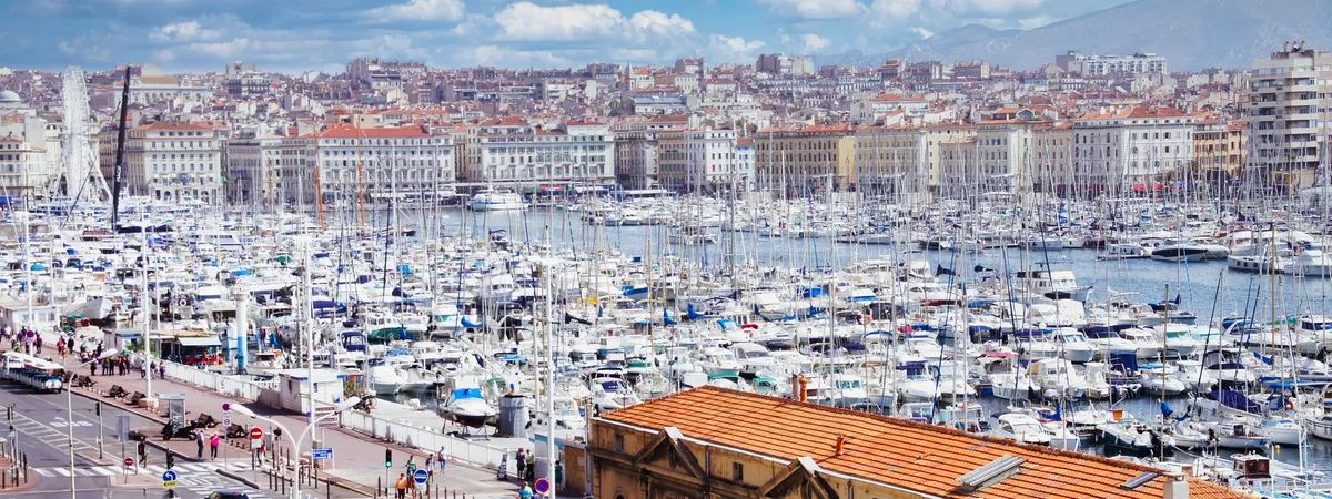 Aerial view of Marseille's Vieux-Port marina packed with sailboats, with the city and hills in the background