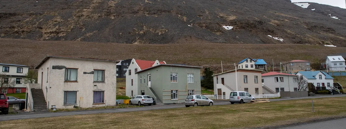 A row of houses along Patreksfjörður’s main street with the bare scree slope rising directly behind them