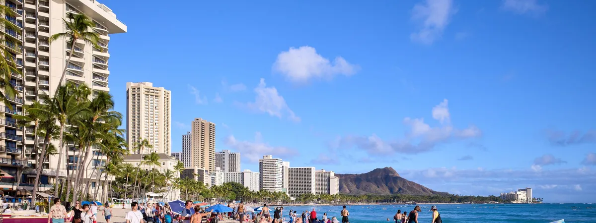 Waikiki Beach lined with high-rise hotels and palm trees, with the Diamond Head crater rising in the distance