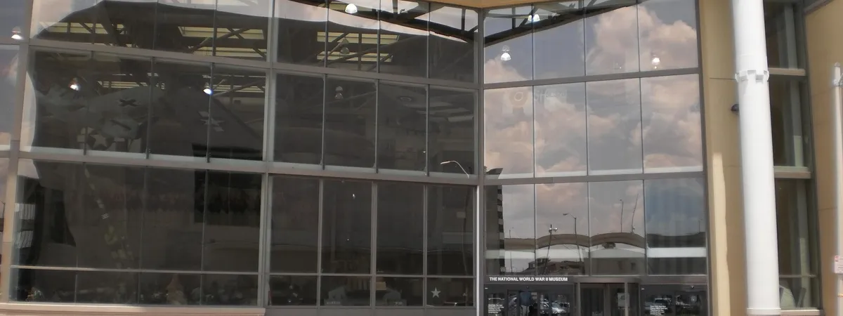 The glass entrance facade of the National WWII Museum, marked with its name, in New Orleans' Warehouse District