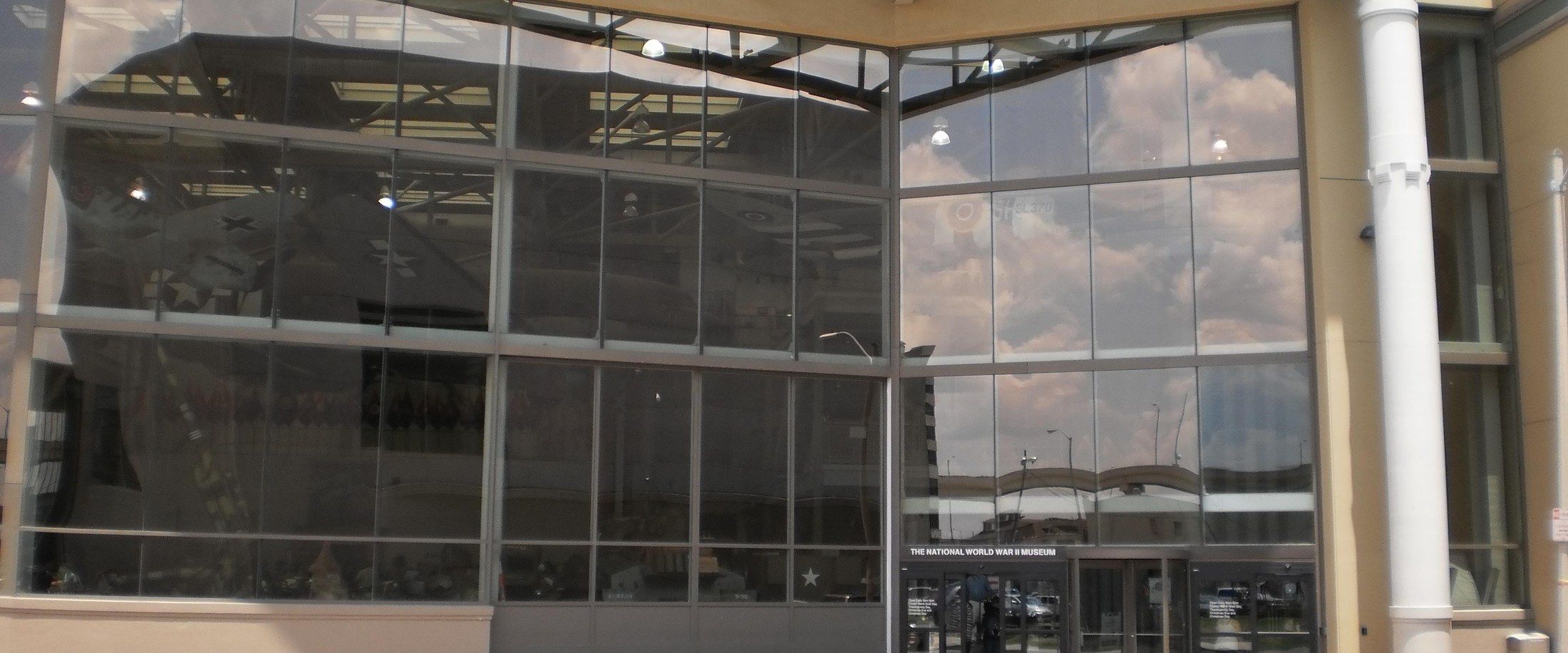 The glass entrance facade of the National WWII Museum, marked with its name, in New Orleans' Warehouse District