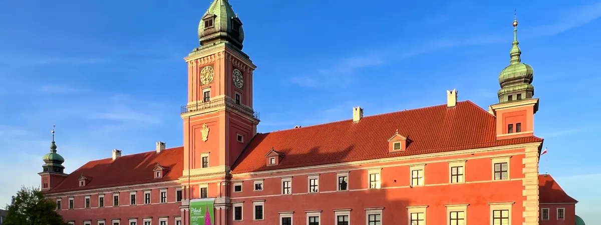 The Royal Castle's red facade and clock tower at Castle Square in Warsaw's Old Town