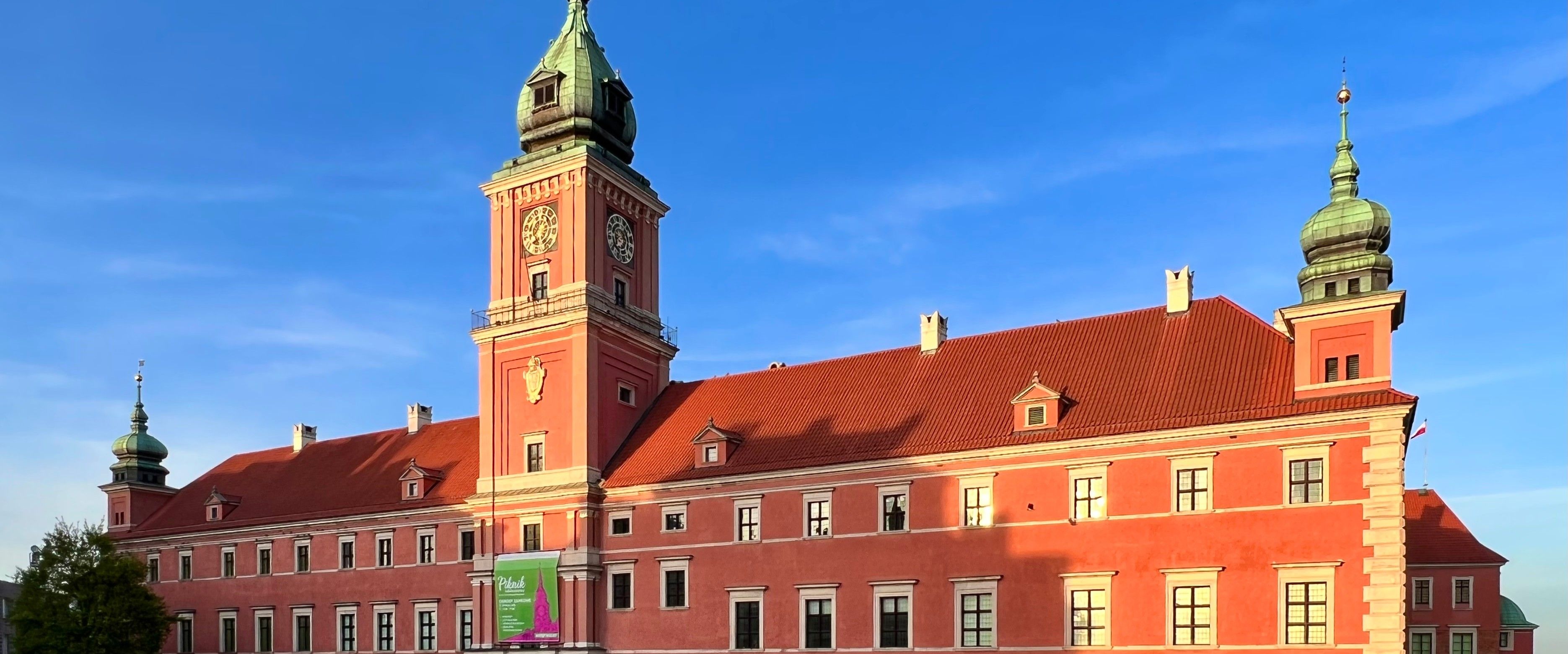 The Royal Castle's red facade and clock tower at Castle Square in Warsaw's Old Town