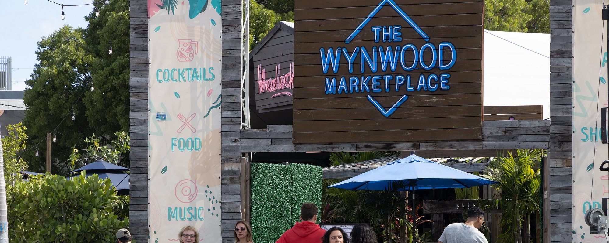 שלט הכניסה מעץ, מואר בניאון, של Wynwood Marketplace, מקום אוכל ומשקאות טיפוסי למרחבי המחסנים המומרים של רובע האמנים