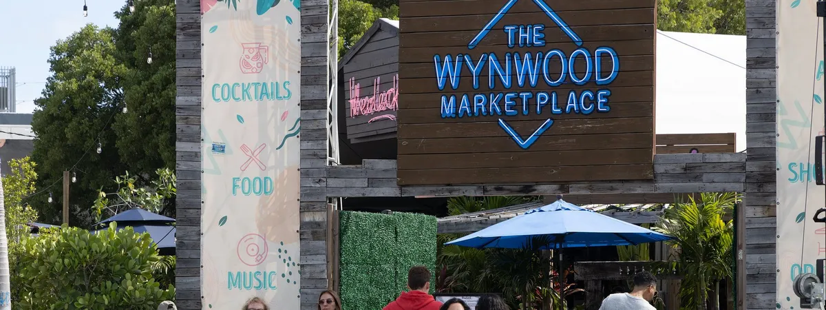 The neon-lit wooden entrance sign for the Wynwood Marketplace, a food-and-drink venue typical of the arts district's converted-warehouse spaces