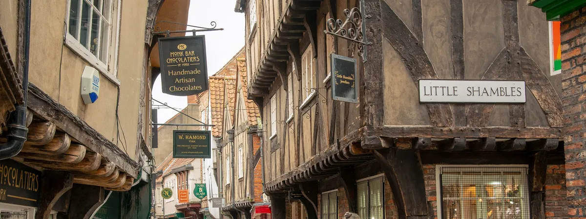 The timber-framed, overhanging shopfronts of the Shambles in York, with the Little Shambles street sign visible