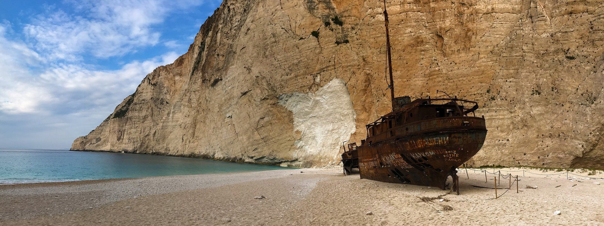 El oxidado naufragio del Panagiotis sobre la arena blanca de la playa de Navagio, enmarcado por altos acantilados de caliza